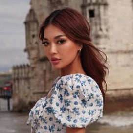 Woman in a floral dress standing by a castle by the water